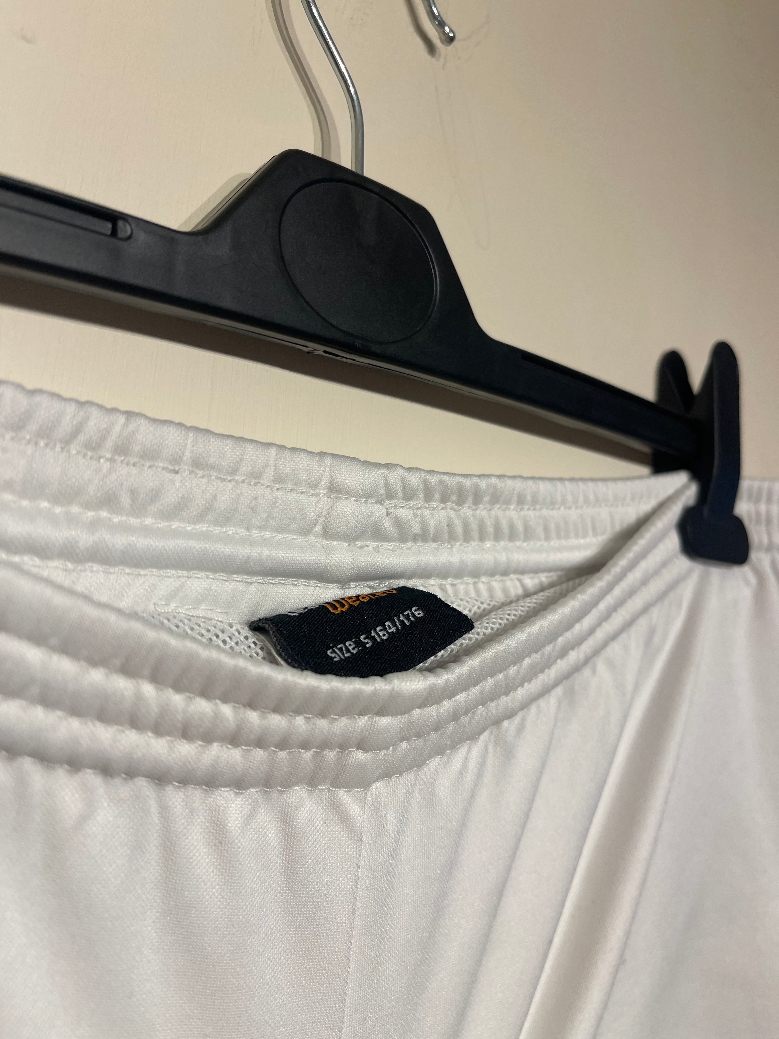 Close-up of a white garment with a black tag on a beige background