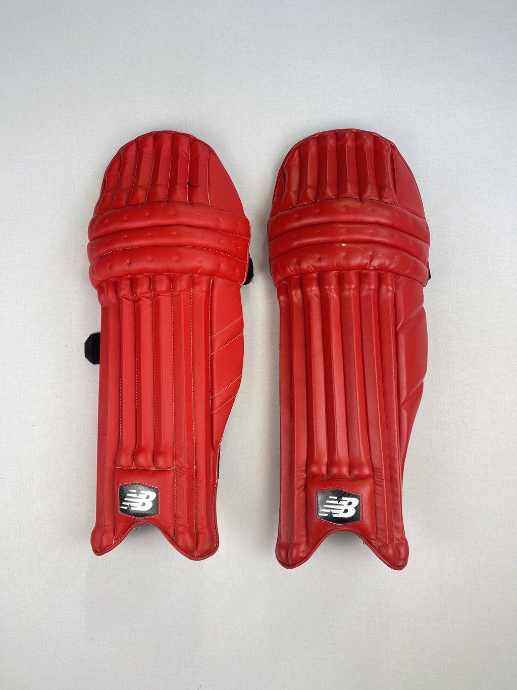 New Balance red youth cricket pads, front